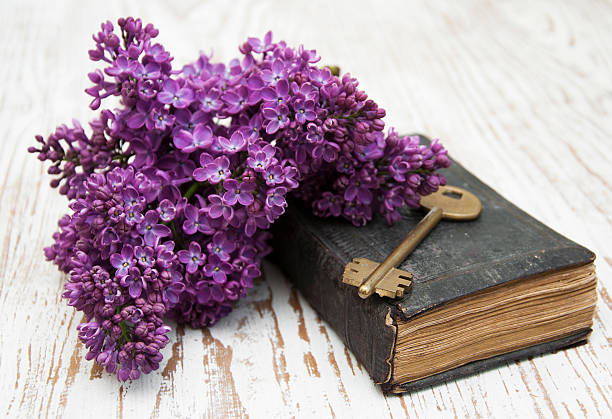 un livre ancien sur lequel est posée une clé avec des fleurs violettes